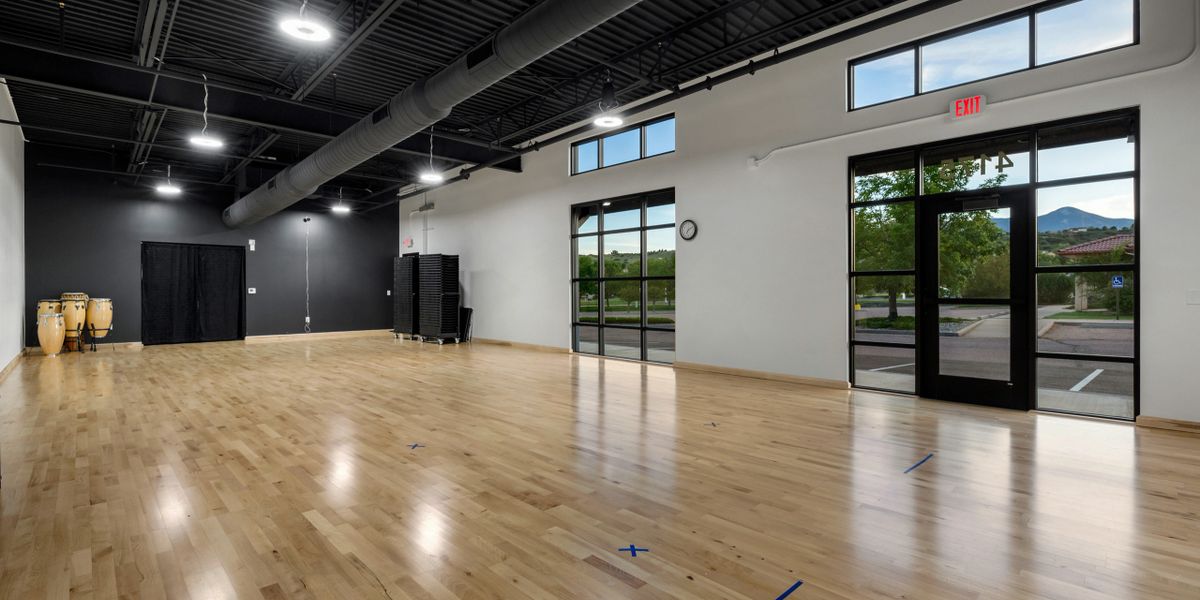 A large studio with wood paneled floors, closet space, mirrors, and large windows