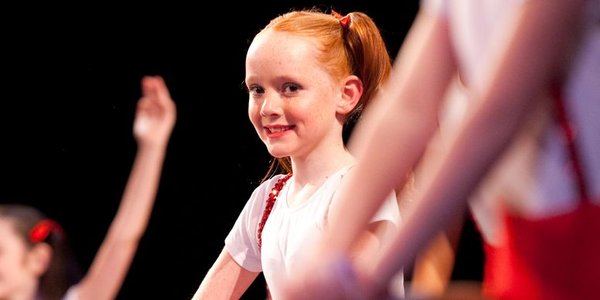 a young red-haired dancer smiling at the camera