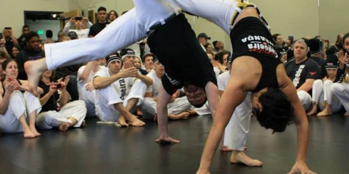 a man and woman doing cartwheels in a capoeira game