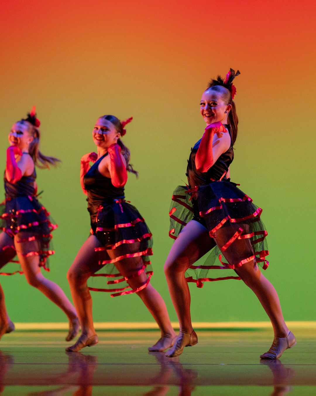 three dancers in red and black outfits performing in front of a yellow and green lighted background