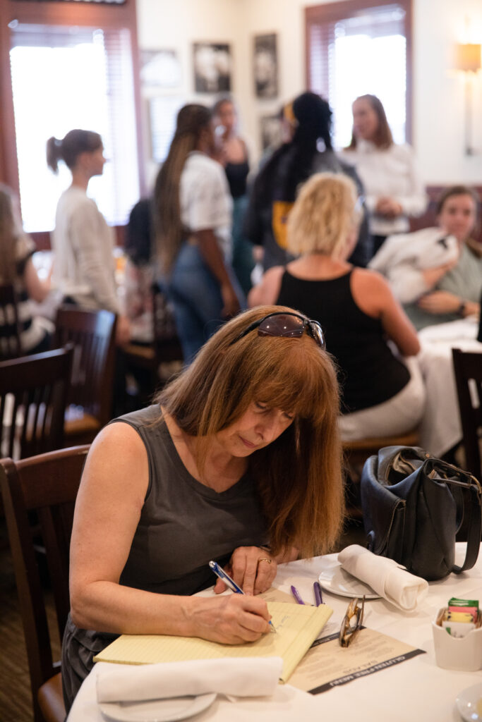 A dance studio owner writing on a notepad at a conference