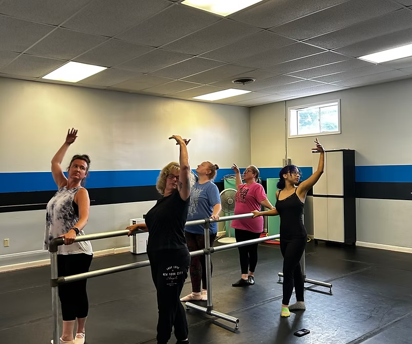 Adult dancers training ballet at the barre