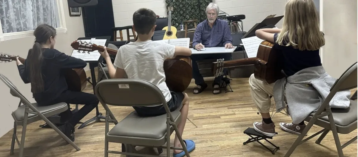 Student attentively listening to the guitar instructor.